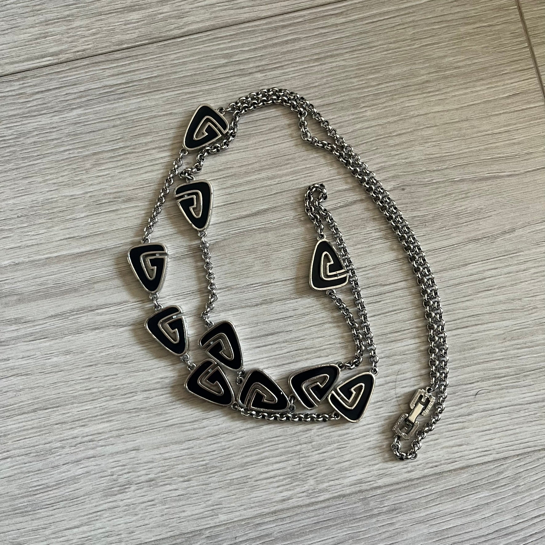 Givenchy Silver Enameled “G” Necklace from the late 1970s to early 1980s, crafted in silver with ten interlinked G-shaped triangular segments filled with black enamel. Signed Givenchy on the clasp. A rare collector’s jewelry item from Givenchy’s early archives.