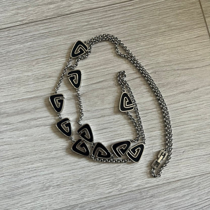 Givenchy Silver Enameled “G” Necklace from the late 1970s to early 1980s, crafted in silver with ten interlinked G-shaped triangular segments filled with black enamel. Signed Givenchy on the clasp. A rare collector’s jewelry item from Givenchy’s early archives.