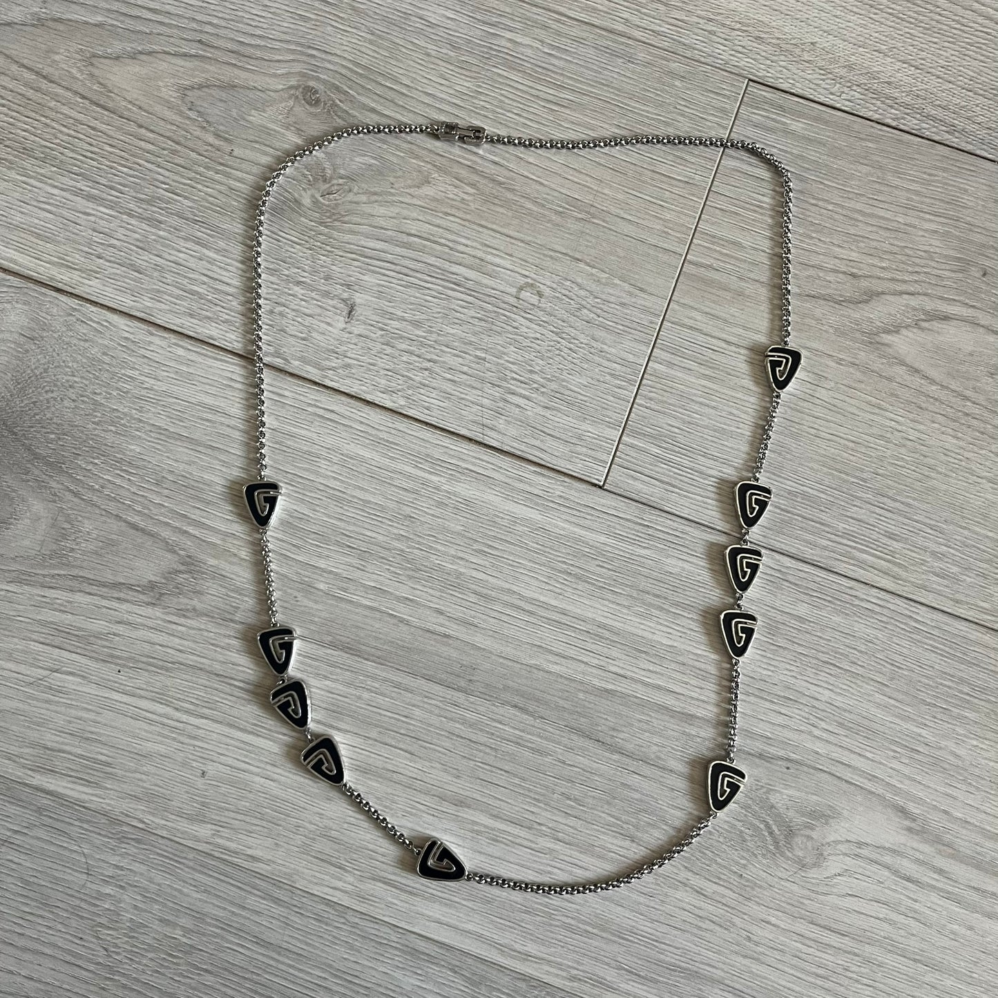Givenchy Silver Enameled “G” Necklace from the late 1970s to early 1980s, crafted in silver with ten interlinked G-shaped triangular segments filled with black enamel. Signed Givenchy on the clasp. A rare collector’s jewelry item from Givenchy’s early archives.