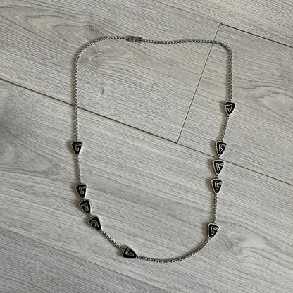 Givenchy Silver Enameled “G” Necklace from the late 1970s to early 1980s, crafted in silver with ten interlinked G-shaped triangular segments filled with black enamel. Signed Givenchy on the clasp. A rare collector’s jewelry item from Givenchy’s early archives.