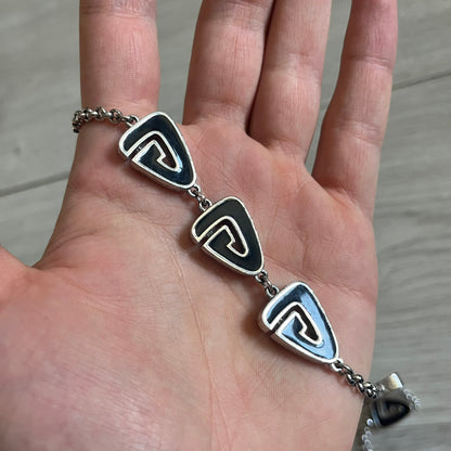 Givenchy Silver Enameled “G” Necklace from the late 1970s to early 1980s, crafted in silver with ten interlinked G-shaped triangular segments filled with black enamel. Signed Givenchy on the clasp. A rare collector’s jewelry item from Givenchy’s early archives.