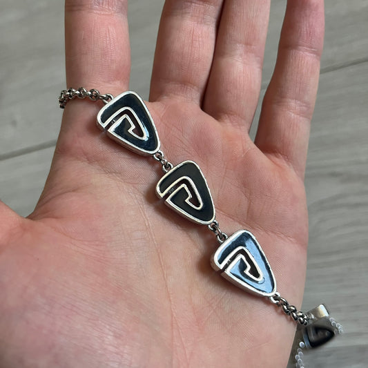 Givenchy Silver Enameled “G” Necklace from the late 1970s to early 1980s, crafted in silver with ten interlinked G-shaped triangular segments filled with black enamel. Signed Givenchy on the clasp. A rare collector’s jewelry item from Givenchy’s early archives.