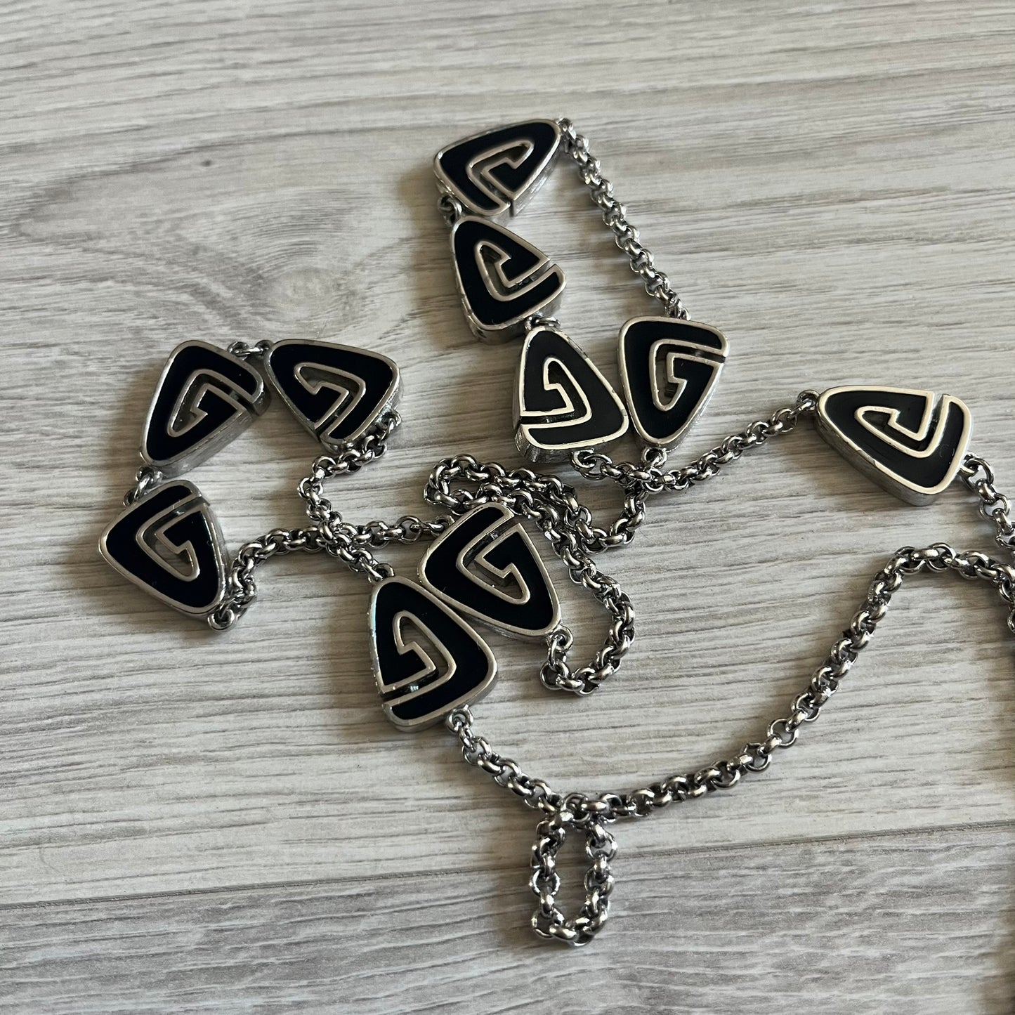 Givenchy Silver Enameled “G” Necklace from the late 1970s to early 1980s, crafted in silver with ten interlinked G-shaped triangular segments filled with black enamel. Signed Givenchy on the clasp. A rare collector’s jewelry item from Givenchy’s early archives.