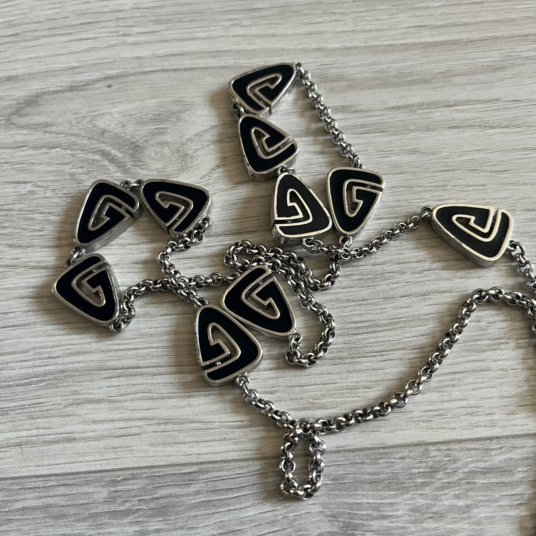 Givenchy Silver Enameled “G” Necklace from the late 1970s to early 1980s, crafted in silver with ten interlinked G-shaped triangular segments filled with black enamel. Signed Givenchy on the clasp. A rare collector’s jewelry item from Givenchy’s early archives.
