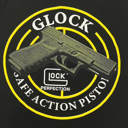 Glock Safe Action Pistol T-Shirt in black, made on an Orijin blank from 100% cotton. Features a large Glock pistol graphic on the front set inside a yellow circle, with “Glock Safe Action” text and Glock logo running around the graphic. The back has a white Glock logo printed below the collar.&nbsp;