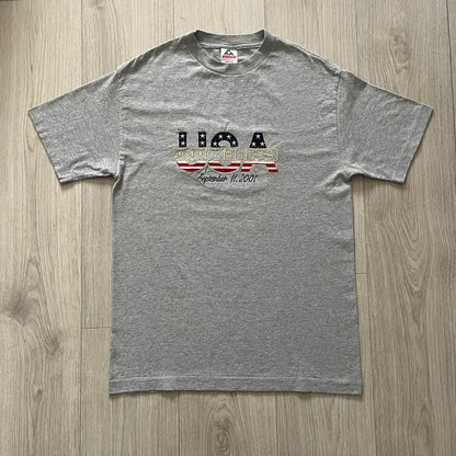 Gray “God Bless USA” tee on an Alstyle blank, made from soft, durable cotton. Embroidery showcases USA in flag colors with gold “God Bless” text and a subtle September 11, 2001 detail underneath. A respectful and collectible commemorative shirt.