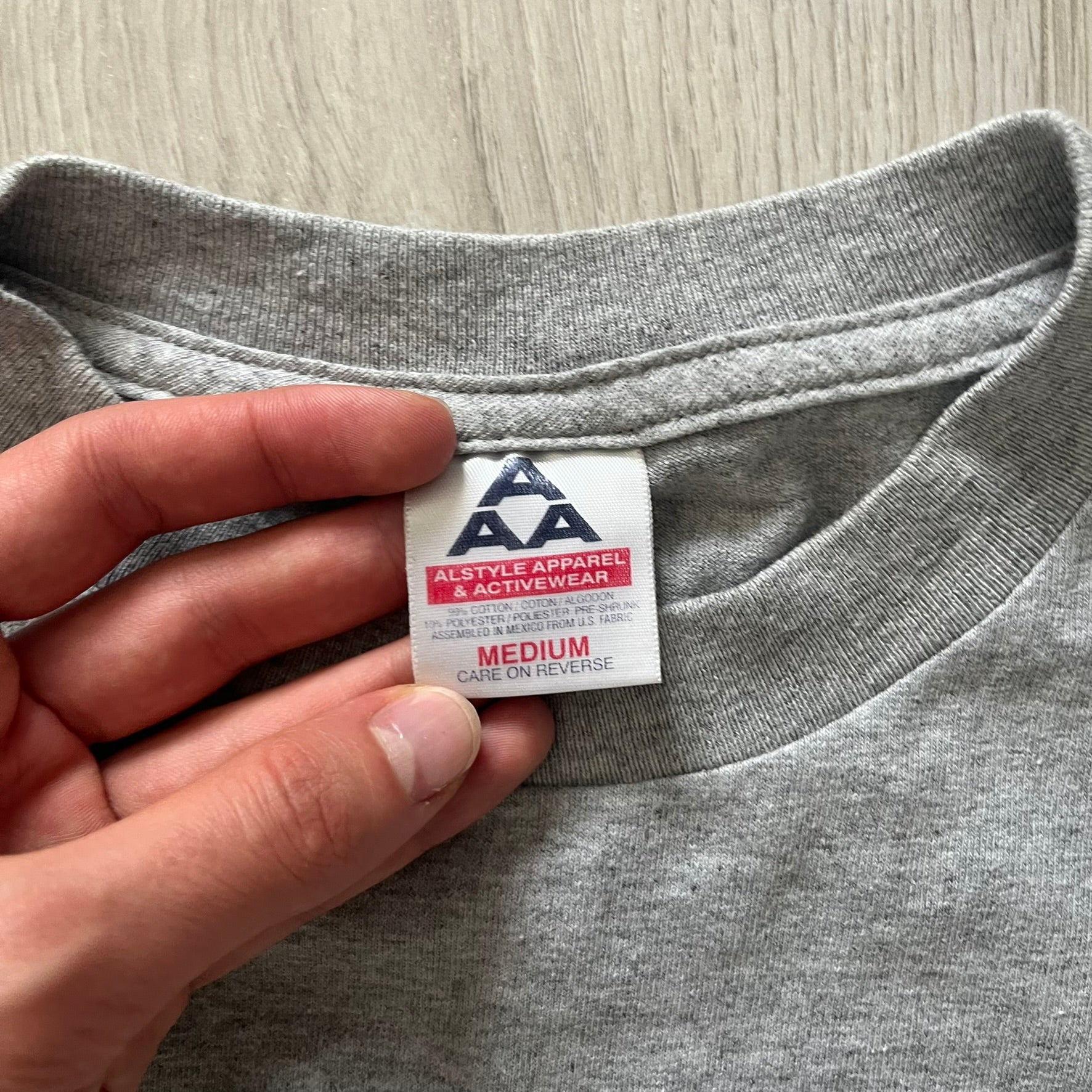 Gray “God Bless USA” tee on an Alstyle blank, made from soft, durable cotton. Embroidery showcases USA in flag colors with gold “God Bless” text and a subtle September 11, 2001 detail underneath. A respectful and collectible commemorative shirt.
