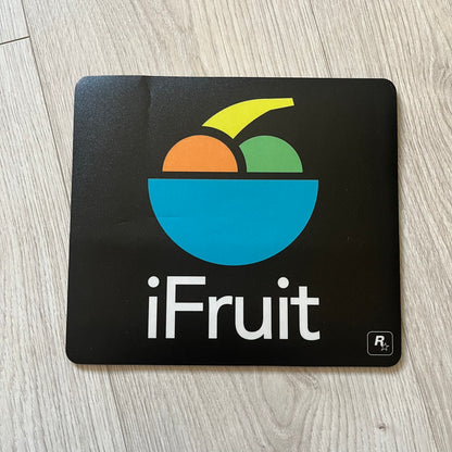 Official Rockstar Games Grand Theft Auto V "iFruit" Mouse Pad. Sleek black hard-plastic surface with a smooth, low-friction finish and the classic iFruit logo in color. Features a durable non-slip rubber base for stability and the Rockstar Games logo at the bottom. Originally available via the Rockstar Warehouse during GTAV’s release period.