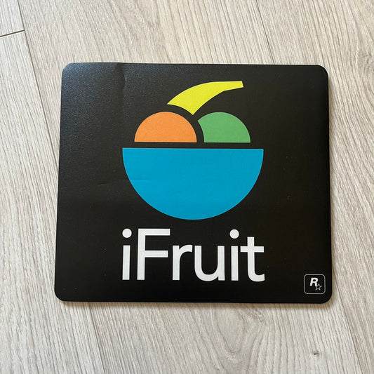 Official Rockstar Games Grand Theft Auto V "iFruit" Mouse Pad. Sleek black hard-plastic surface with a smooth, low-friction finish and the classic iFruit logo in color. Features a durable non-slip rubber base for stability and the Rockstar Games logo at the bottom. Originally available via the Rockstar Warehouse during GTAV’s release period.