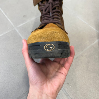 Gucci 2000’s Beige & Brown Shearling Lined Boots are made in Italy from beige and brown suede with a shearling-lined interior. A velcro strap with a Gucci logo closes the top, and the tongue has a leather tab with the Gucci logo. A green and red stripe runs around the top, a GG logo is on the side, and another GG logo appears on the sole along with a small one at the toe tip and a brown leather Gucci logo section on the sole. Due to age, the sole is falling apart and needs either gluing or a sole replacemen