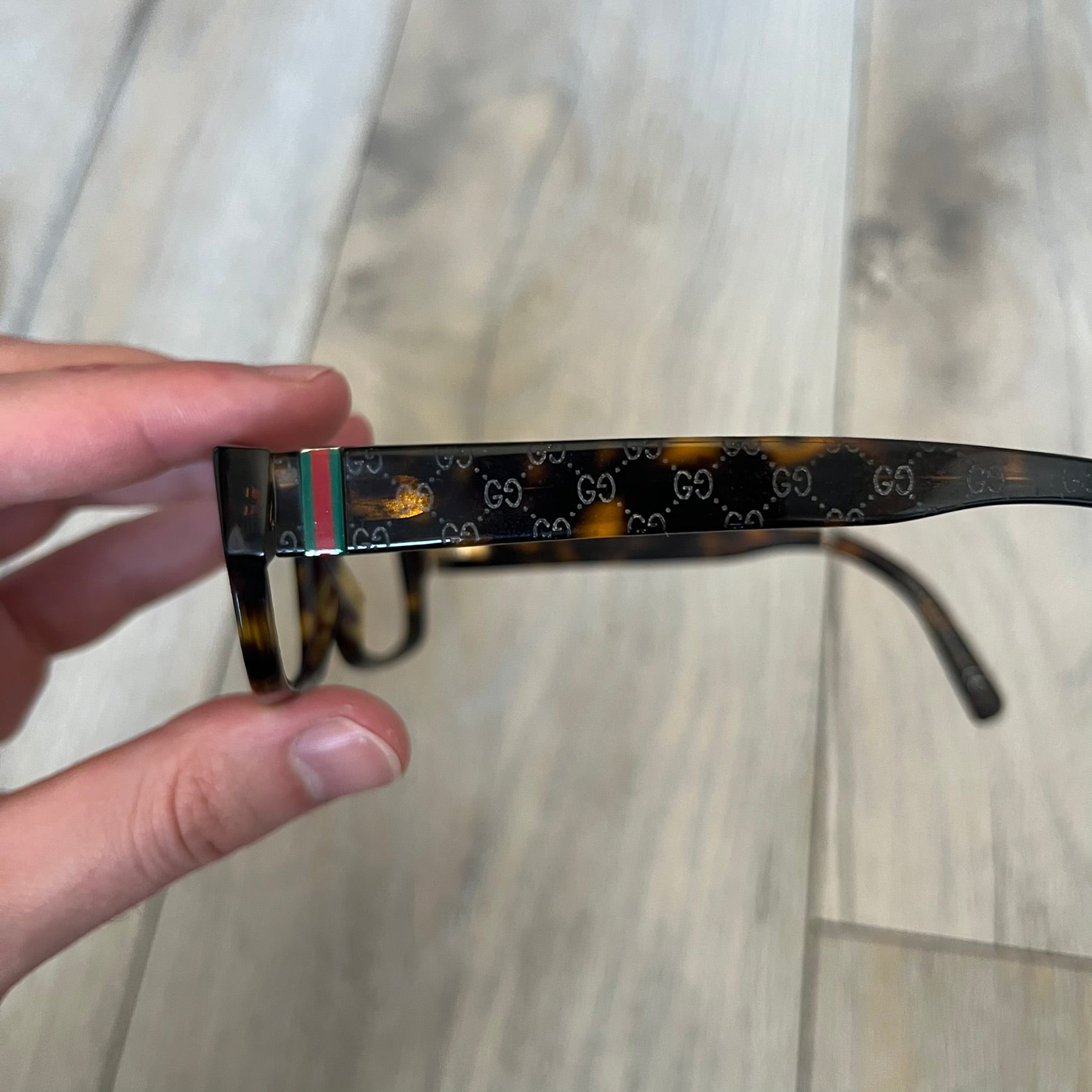 Gucci GG 3080 086 Glasses Frames are eyeglass frames made in Italy, featuring a brown and orange-toned acetate construction. The temples are detailed with silver GG monogram pattern accents and Gucci’s signature red and green web stripe near the front of the arms. The frames come with a matching monogram Gucci case.