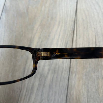 Gucci GG 3080 086 Glasses Frames are eyeglass frames made in Italy, featuring a brown and orange-toned acetate construction. The temples are detailed with silver GG monogram pattern accents and Gucci’s signature red and green web stripe near the front of the arms. The frames come with a matching monogram Gucci case.