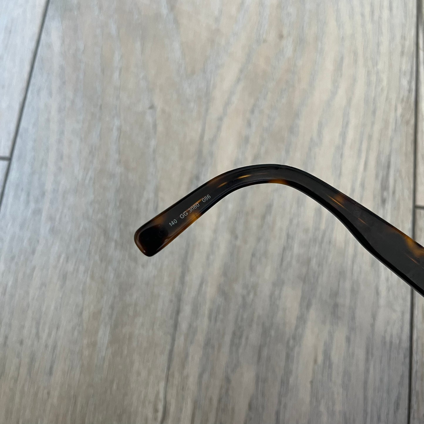 Gucci GG 3080 086 Glasses Frames are eyeglass frames made in Italy, featuring a brown and orange-toned acetate construction. The temples are detailed with silver GG monogram pattern accents and Gucci’s signature red and green web stripe near the front of the arms. The frames come with a matching monogram Gucci case.