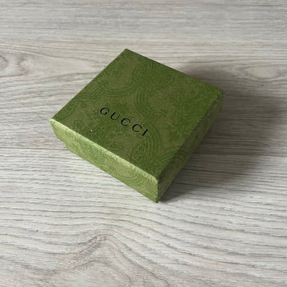 Green Gucci jewelry box on a wooden surface