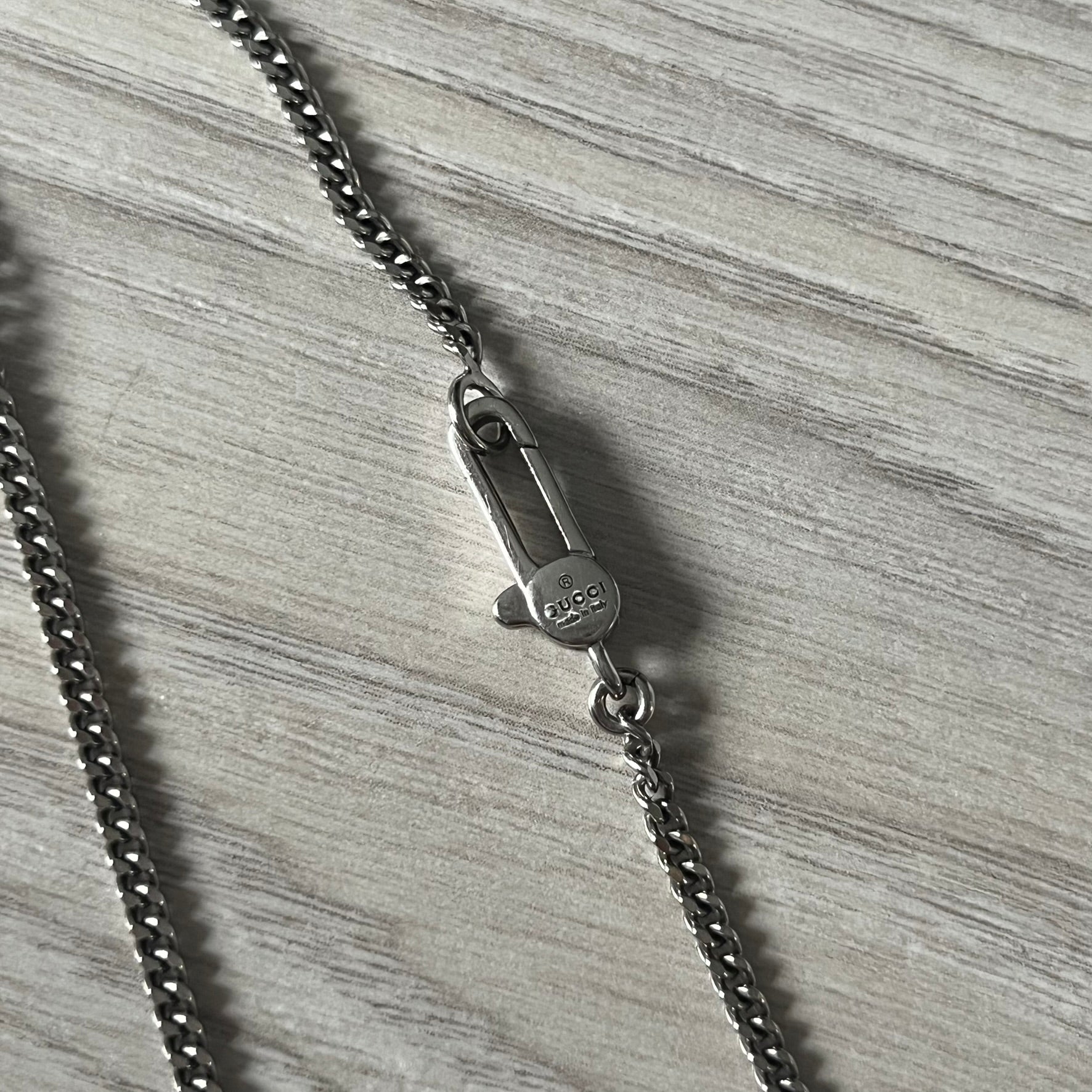 Close-up of a silver chain with clasp on a textured gray surface