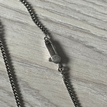 Close-up of a silver chain with clasp on a textured gray surface