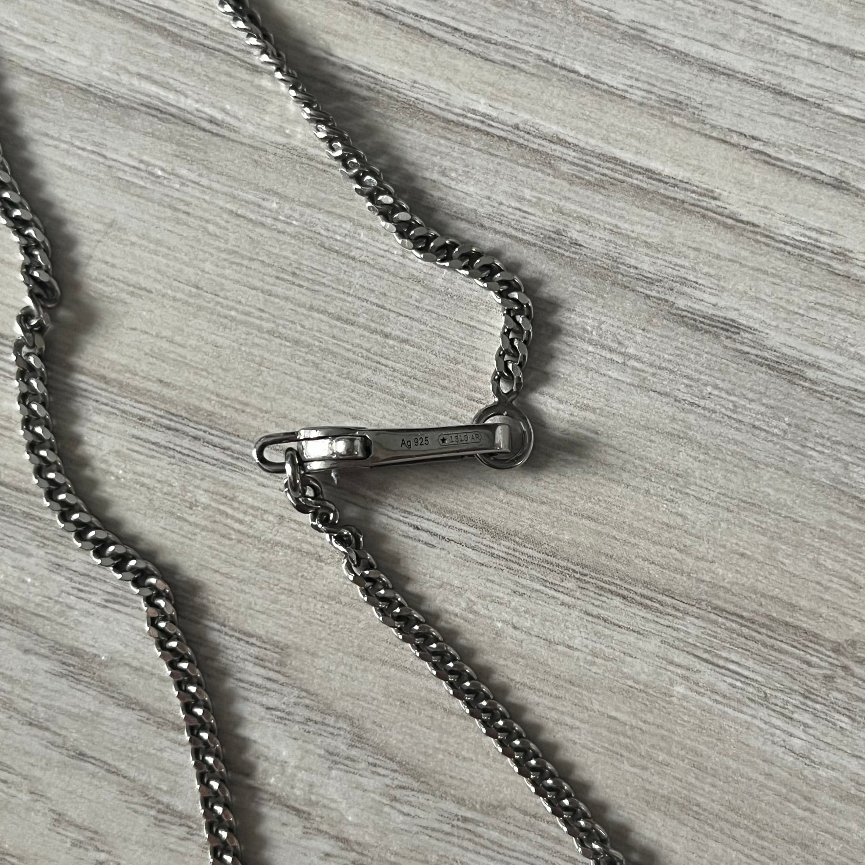 Close-up of a black chain necklace on a wooden surface