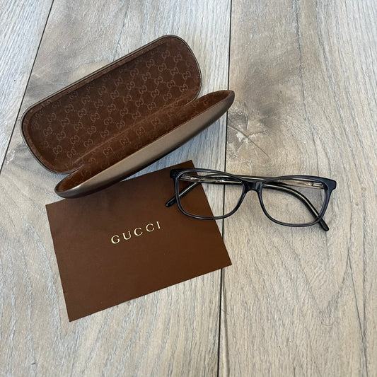 Gucci Gray-Blue Glasses Frames feature a translucent gray and dark blue acetate construction with a clear finish. Small silver GG logos are positioned on the front sides of the frames near the hinges. The frames are sold without lenses and come with a Gucci monogram case and a brown cleaning cloth.