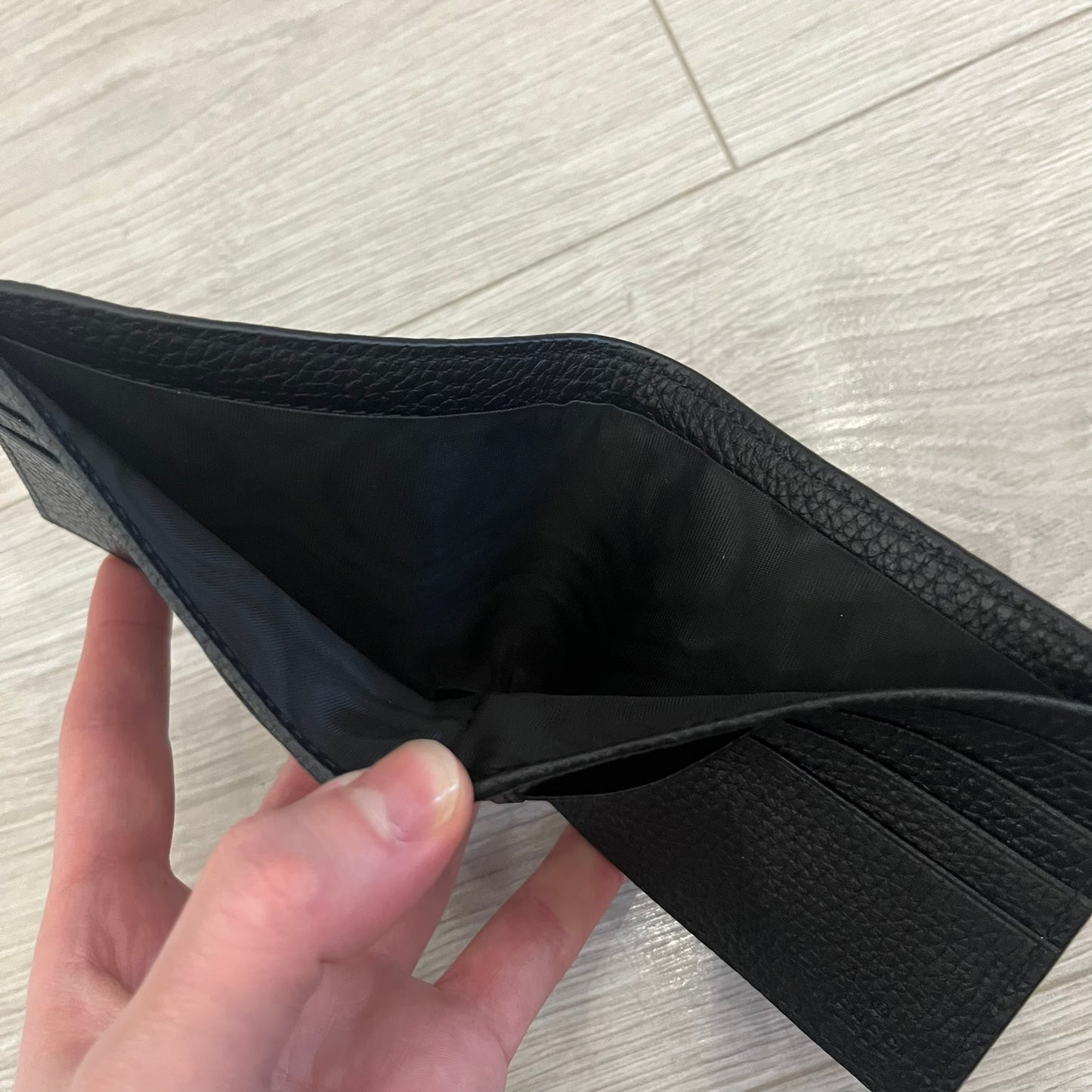 Gucci Jumbo GG Bi-Fold Leather Wallet in black calfskin, featuring the brand’s iconic debossed Jumbo GG logo. This Italian-made wallet offers eight card slots, two bill compartments, and a bi-fold design for organized storage. Finished with grained leather and a moiré lining.