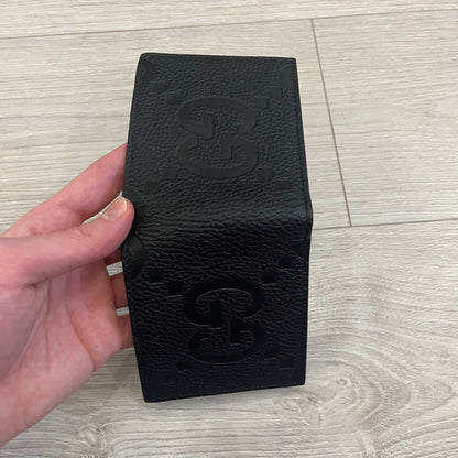 Gucci Jumbo GG Bi-Fold Leather Wallet in black calfskin, featuring the brand’s iconic debossed Jumbo GG logo. This Italian-made wallet offers eight card slots, two bill compartments, and a bi-fold design for organized storage. Finished with grained leather and a moiré lining.