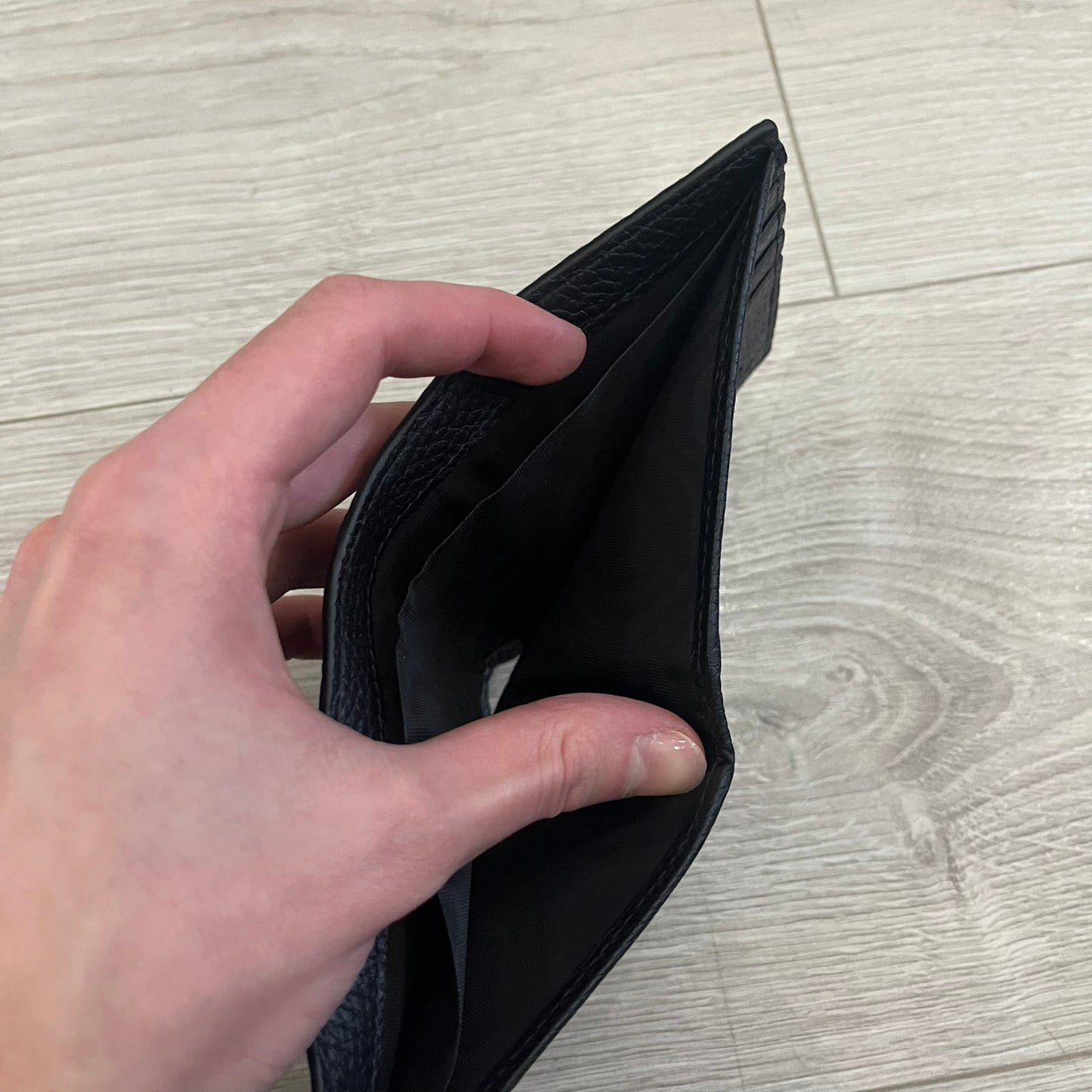 Gucci Jumbo GG Bi-Fold Leather Wallet in black calfskin, featuring the brand’s iconic debossed Jumbo GG logo. This Italian-made wallet offers eight card slots, two bill compartments, and a bi-fold design for organized storage. Finished with grained leather and a moiré lining.