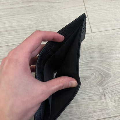 Gucci Jumbo GG Bi-Fold Leather Wallet in black calfskin, featuring the brand’s iconic debossed Jumbo GG logo. This Italian-made wallet offers eight card slots, two bill compartments, and a bi-fold design for organized storage. Finished with grained leather and a moiré lining.