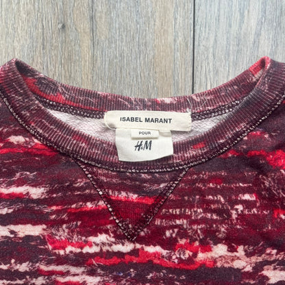 H&amp;M x Isabel Marant 2013 Red Disorder Sweater is a women’s knit sweater in red, made from a soft fabric blend. The sweater features a deliberately distressed knit throughout, with ribbed cuffs and hem for structure. It was released as part of the H&amp;M x Isabel Marant 2013 collaboration