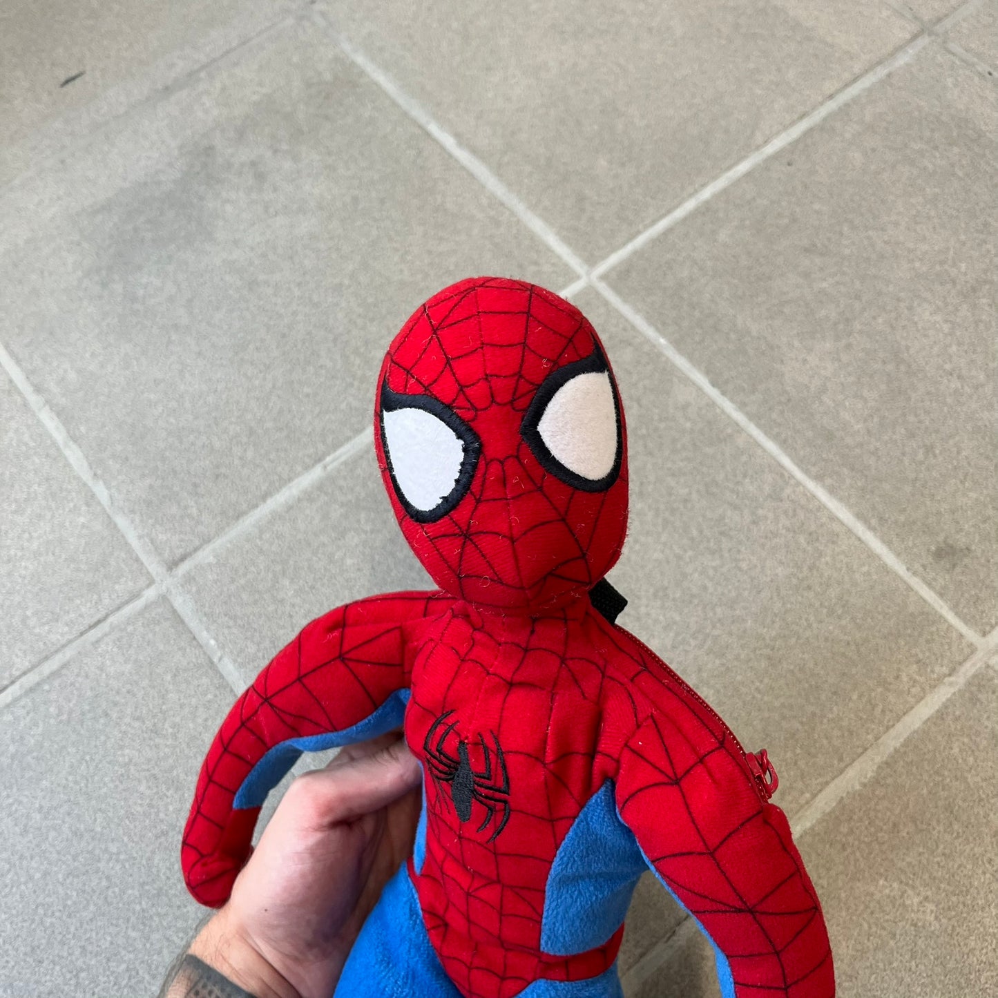 H&M x Marvel 2006 Spider-Man Backpack is a red and blue backpack shaped like Spider-Man in his signature costume. The design features embroidered eye details and an embroidered spider logo on the chest. It has a compact back pocket and straps connected from the character’s hands to the legs. Includes 2006 H&M x Marvel licensing details.
