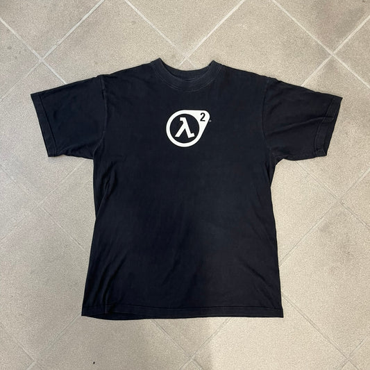 Half-Life 2 2000’s Lambda Black Tee is a black, 100% cotton T-shirt with a white Half-Life 2 logo on the front, showing the lambda symbol inside a circle with a “2” in the corner and a small TM mark beside it.