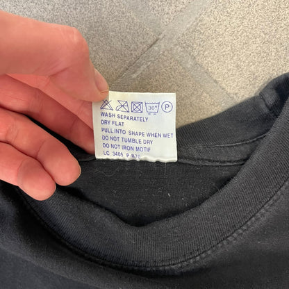 Half-Life 2 2000’s Lambda Black Tee is a black, 100% cotton T-shirt with a white Half-Life 2 logo on the front, showing the lambda symbol inside a circle with a “2” in the corner and a small TM mark beside it.