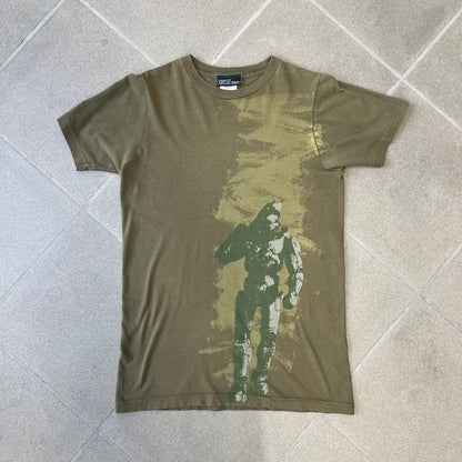Halo 3 Finish the Fight 2006 Tee is a khaki, 100% cotton T-shirt with a green Master Chief graphic on the front against a lighter background. A Halo 3 logo is on one sleeve, and “Finish the Fight” text runs across the upper back. The neck tag is licensed for Xbox 360 and carries 2005 licensing on the other side.