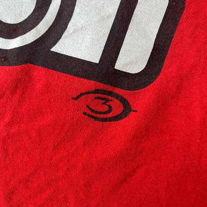 Halo 3 Grunt Emblem 2007 Red Tee features a red T-shirt made on a Gildan blank. The front has a large white and black Grunt emblem graphic, with a small Halo 3 logo below it on the right and Microsoft 2007 licensing text below it on the left. Made from 100% cotton.
