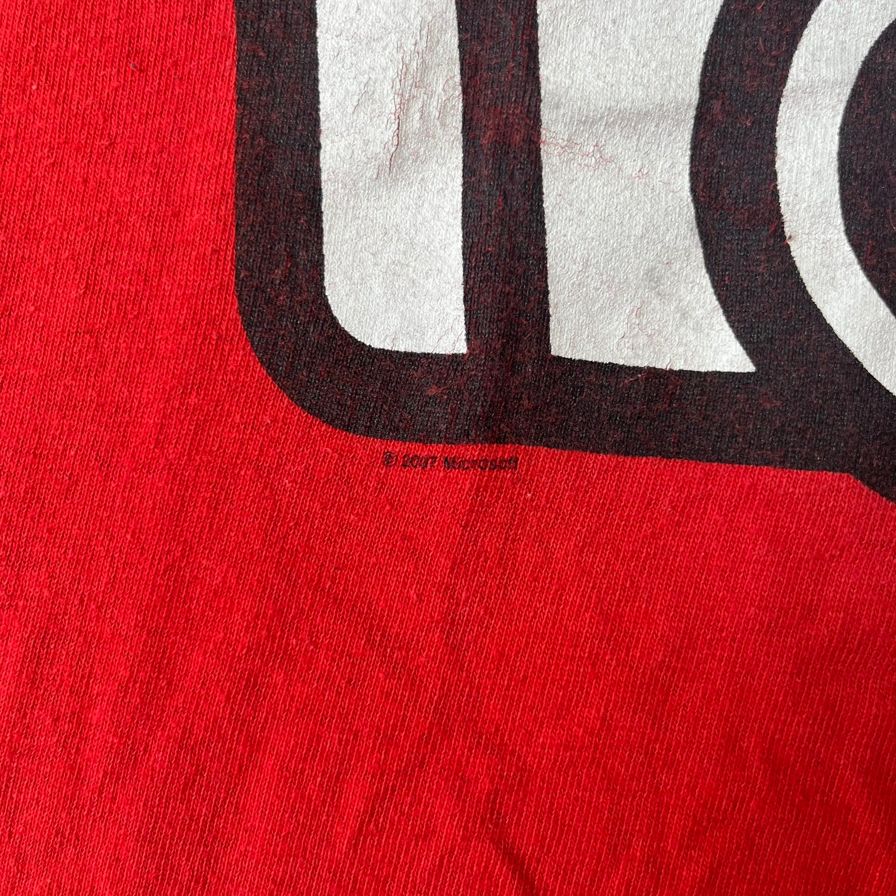 Halo 3 Grunt Emblem 2007 Red Tee features a red T-shirt made on a Gildan blank. The front has a large white and black Grunt emblem graphic, with a small Halo 3 logo below it on the right and Microsoft 2007 licensing text below it on the left. Made from 100% cotton.
