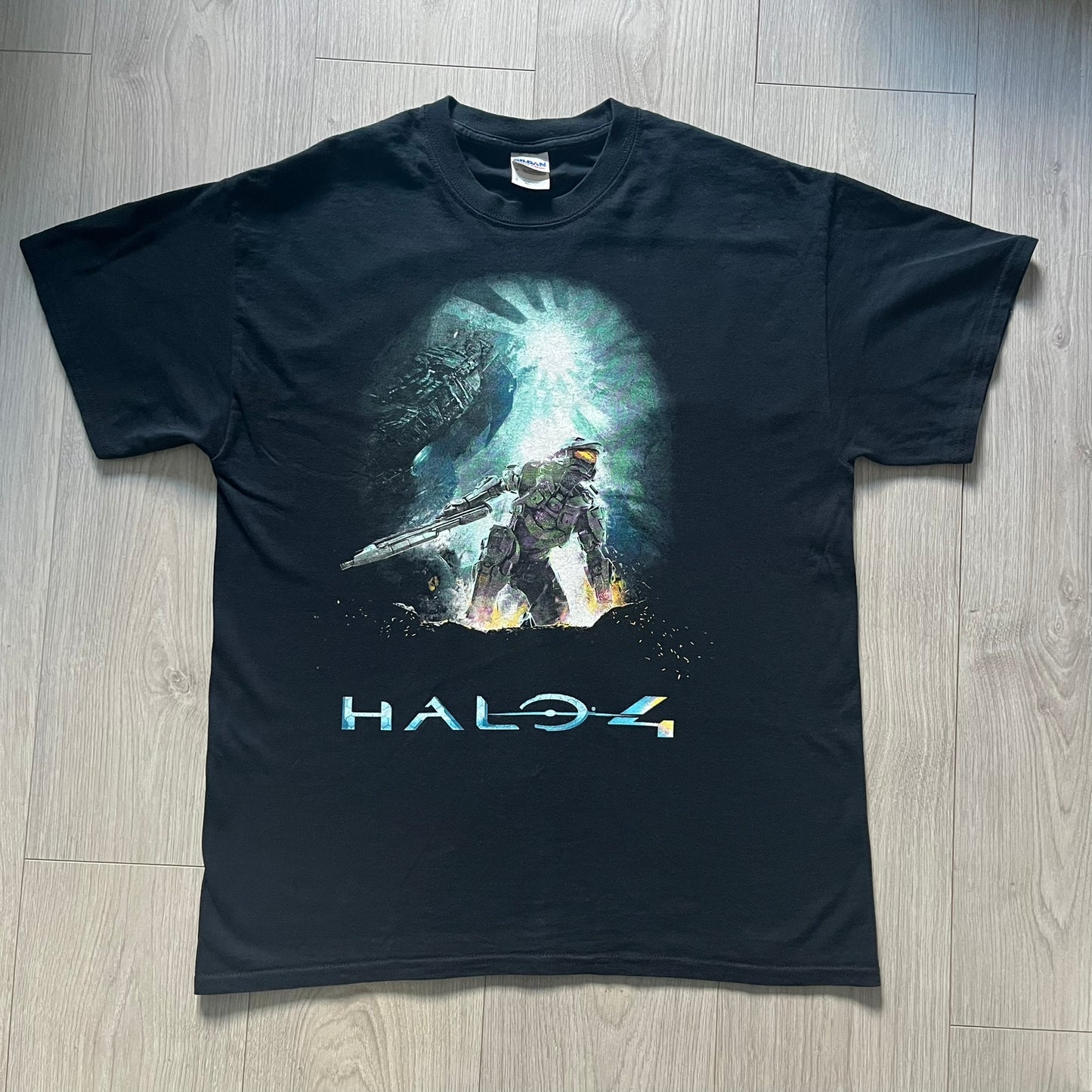 Halo 4 cover tee from 2012, printed on black Gildan heavy cotton. Features the iconic game cover artwork with Master Chief and beautiful Halo 4 text underneath. A collectible piece for Xbox and Halo fans.