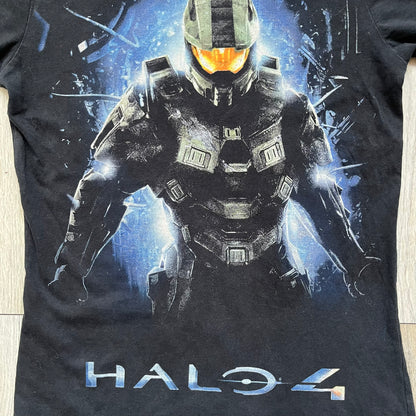 Halo 4 Master Chief 2012 Tee is a black graphic T-shirt featuring a large front print of Master Chief standing in front of a blue sci-fi style background. The design includes a detailed illustration of the character with a large Halo 4 logo printed below the graphic. The shirt has a 2012 Microsoft licensed neck tag.