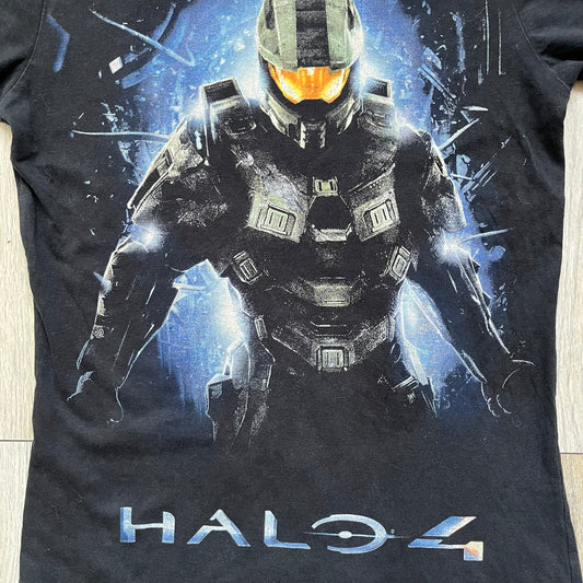 Halo 4 Master Chief 2012 Tee is a black graphic T-shirt featuring a large front print of Master Chief standing in front of a blue sci-fi style background. The design includes a detailed illustration of the character with a large Halo 4 logo printed below the graphic. The shirt has a 2012 Microsoft licensed neck tag.