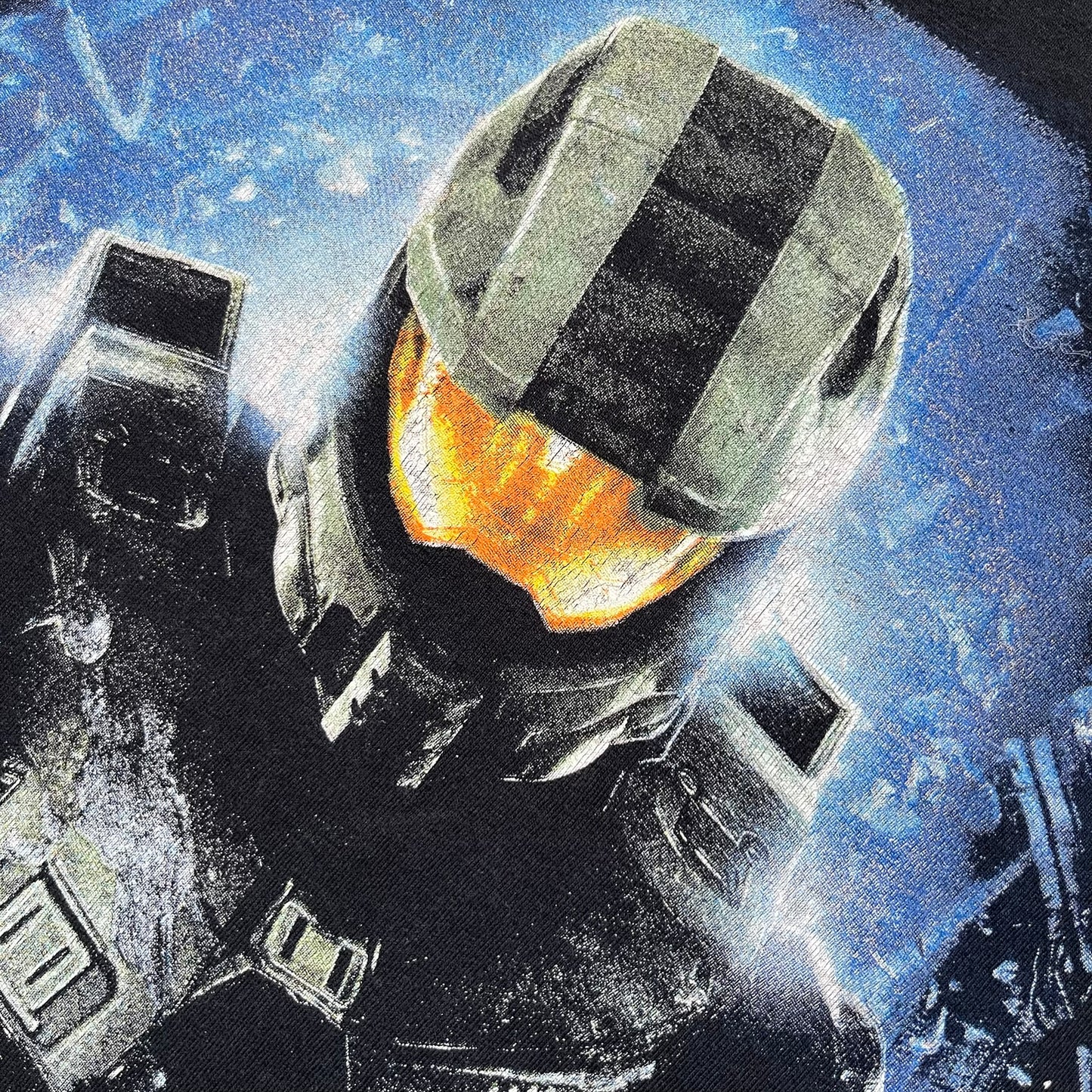 Halo 4 Master Chief 2012 Tee is a black graphic T-shirt featuring a large front print of Master Chief standing in front of a blue sci-fi style background. The design includes a detailed illustration of the character with a large Halo 4 logo printed below the graphic. The shirt has a 2012 Microsoft licensed neck tag.