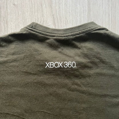 Khaki Halo Reach tee on a Sol’s blank featuring the Noble Team emblem in white on the front and the Halo Reach logo beneath. Small Xbox 360 logo embroidered under the back collar. A classic collectible for fans of the iconic game series.