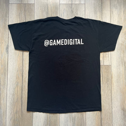 Halo The Master Chief Collection 2010s Tee is a black short-sleeve T-shirt featuring a front graphic of Master Chief’s helmet with golden-orange visor, surrounded by smaller Master Chief figures. The back displays white “@GAMEDIGITAL” text, referencing the gaming merchandise website. This T-shirt was produced as part of official Halo merchandise in the 2010s.