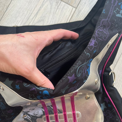 Hannah Montana 2000s Guitar-Shaped Shoulder Bag is a guitar-shaped bag with a black main body. The shoulder strap features pink glossy detailing and white string-like elements. The front panel has a multicolor pattern with stars, flowers, and butterflies. A large silver patch with pink string details and Hannah Montana graphics is placed on the front. The zipper pull is shaped with a Hannah Montana series logo design.
