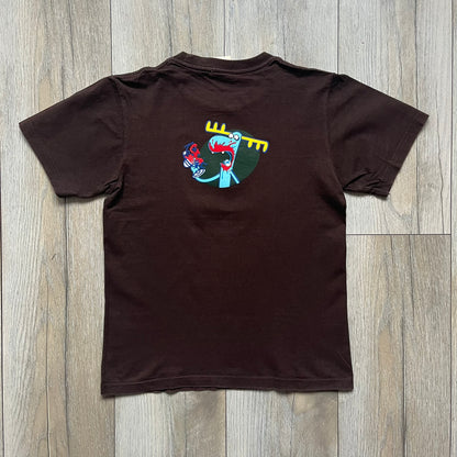 Happy Tree Friends Lumpy Fan Brown Tee from 2005 is a brown T-shirt featuring Lumpy on the front holding and licking a fan. On the back, the same Lumpy graphic appears without the tongue, with visible blood on the fan and face. A small Happy Tree Friends logo is printed in the lower front corner, and the neck tag features a red heart detail.