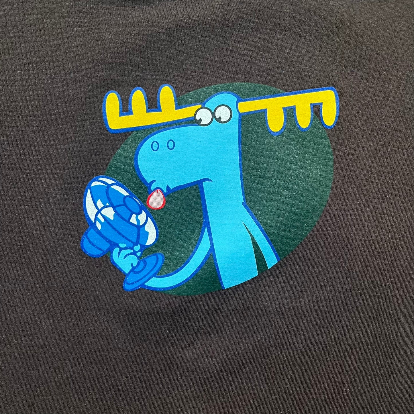 Happy Tree Friends Lumpy Fan Brown Tee from 2005 is a brown T-shirt featuring Lumpy on the front holding and licking a fan. On the back, the same Lumpy graphic appears without the tongue, with visible blood on the fan and face. A small Happy Tree Friends logo is printed in the lower front corner, and the neck tag features a red heart detail.