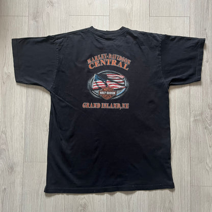  Harley Davidson Grand Island 2000’s Tee featuring a fiery Harley Davidson Motorcycles logo on the front and a USA flag graphic with Harley branding and “Grand Island, NE” text on the back. Classic black vintage tee with a timeless biker aesthetic.