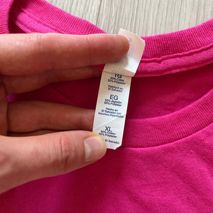 Hand holding a pink garment with a label showing size and material details.