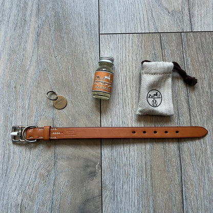 Small model Hermès Étrivière dog collar crafted from Natural Sable bridle leather. The collar features a stirrup-shaped buckle stamped HERMÈS, a metal D-ring for leash attachment, and leather stamped “HERMÈS PARIS MADE IN FRANCE.” It includes a 2 cm silver-plated stainless steel medal engraved “Hermès Sellier Paris,” with the reverse side suitable for engraving