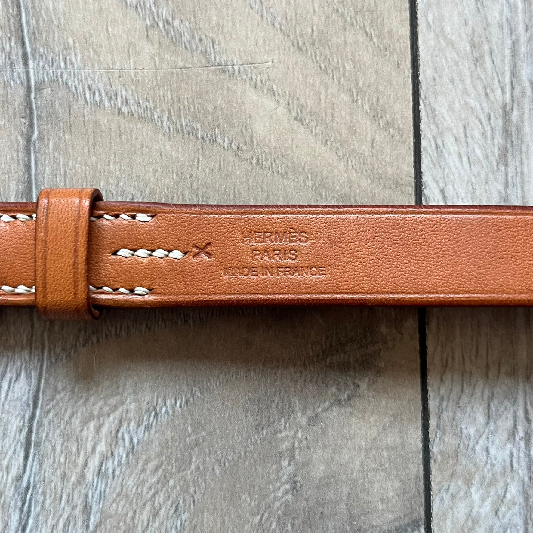 Small model Hermès Étrivière dog collar crafted from Natural Sable bridle leather. The collar features a stirrup-shaped buckle stamped HERMÈS, a metal D-ring for leash attachment, and leather stamped “HERMÈS PARIS MADE IN FRANCE.” It includes a 2 cm silver-plated stainless steel medal engraved “Hermès Sellier Paris,” with the reverse side suitable for engraving
