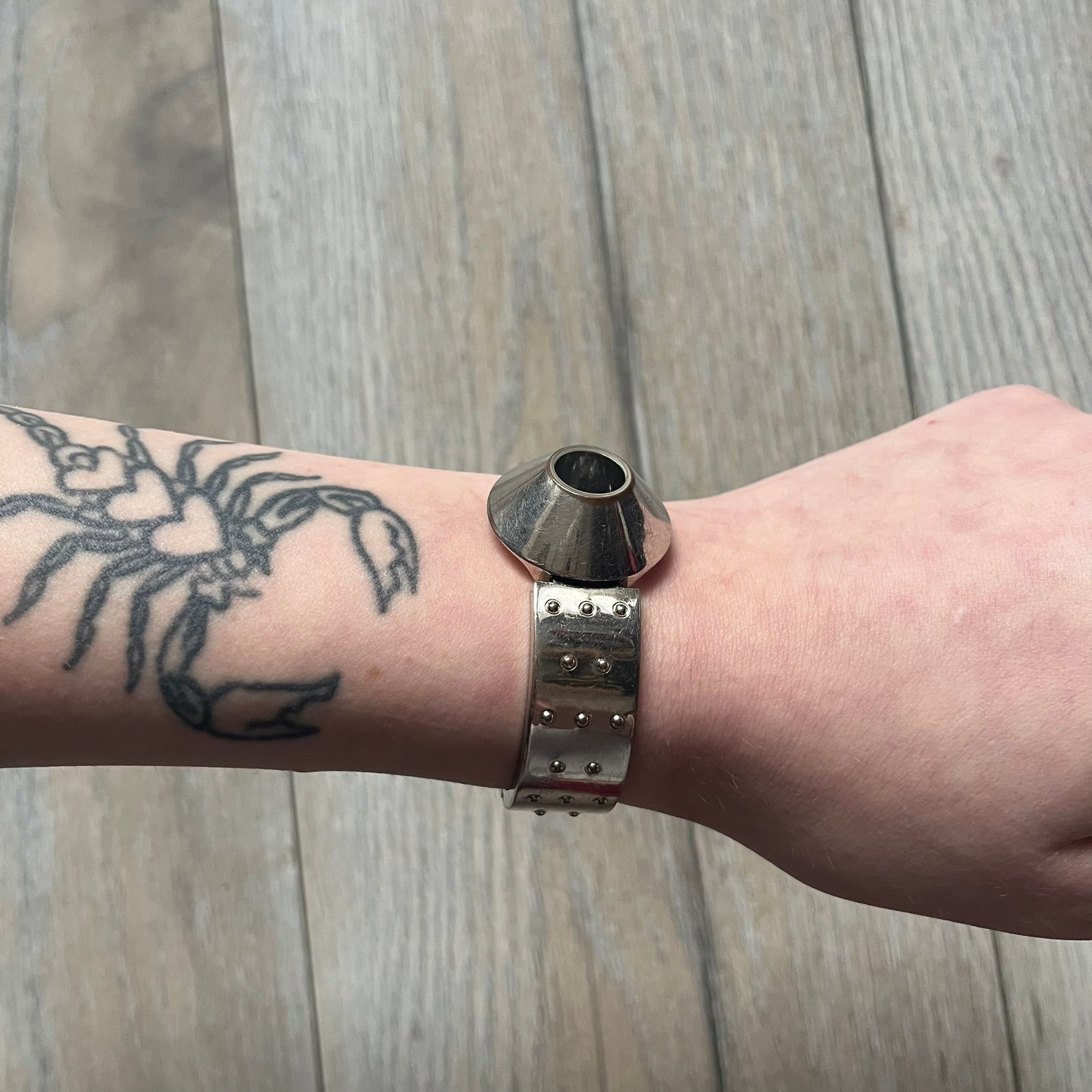 Hi-Tek Alexander “Cylinder” 90’s Analog Watch is a 1990s English-made timepiece featuring a black dial with a small Hi-Tek logo as the seconds hand. The cylindrical 3D case rises from the wrist, making the dial visible only from above, and the straps feature raised dot detailing. The stainless steel case back is branded with the Hi-Tek logo, designed specifically for smaller wrists.