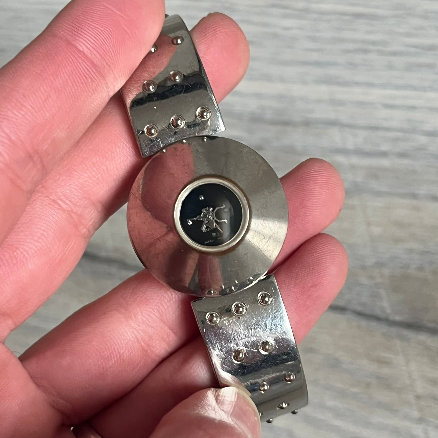 Hi-Tek Alexander “Cylinder” 90’s Analog Watch is a 1990s English-made timepiece featuring a black dial with a small Hi-Tek logo as the seconds hand. The cylindrical 3D case rises from the wrist, making the dial visible only from above, and the straps feature raised dot detailing. The stainless steel case back is branded with the Hi-Tek logo, designed specifically for smaller wrists.