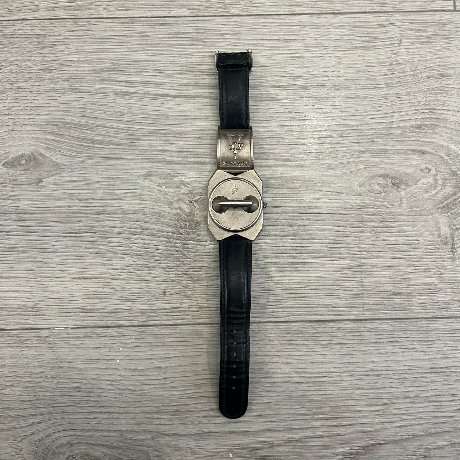 Hi-Tek Alexander “Jump Hour” 90's Analog Watch with a rare octagonal steel case and innovative rotation disc display. Hours appear in the left window and minutes in the right, revealed by the unique turnable cover. Made in England, this vintage 1990s watch features a chrome-plated stainless steel case, genuine leather strap, and an original design by Alexander Tasou of Hi-Tek Designs London. A true collector’s piece that is no longer in production.