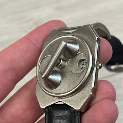 Hi-Tek Alexander “Jump Hour” 90's Analog Watch with a rare octagonal steel case and innovative rotation disc display. Hours appear in the left window and minutes in the right, revealed by the unique turnable cover. Made in England, this vintage 1990s watch features a chrome-plated stainless steel case, genuine leather strap, and an original design by Alexander Tasou of Hi-Tek Designs London. A true collector’s piece that is no longer in production.